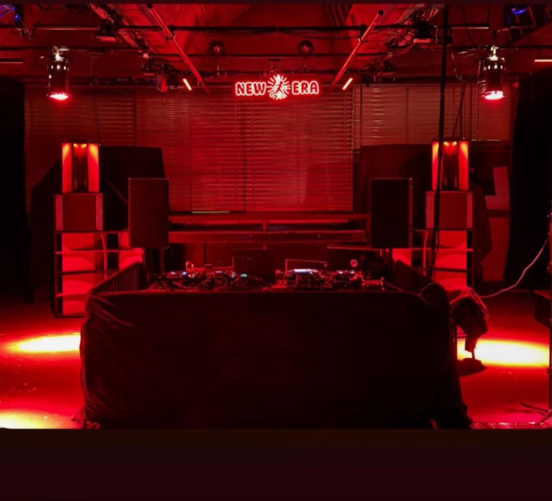 Red-lit New Era stage with speakers and neon sign