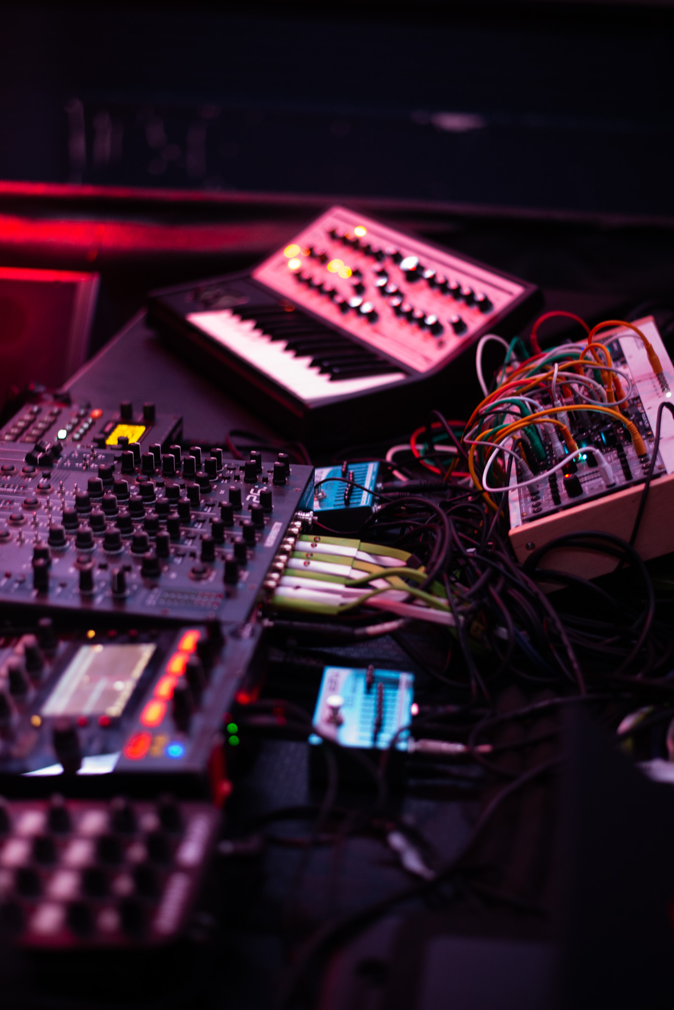 Close up of a DJ mixer and synth cables under pink light